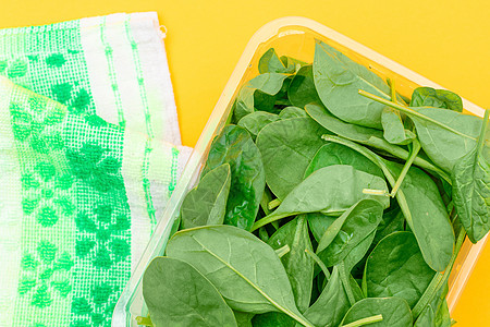 黄色背景透明塑料套件中新鲜的婴儿菠菜叶新片草本植物饮食排毒沙拉树叶绿色食物生食植物活食图片