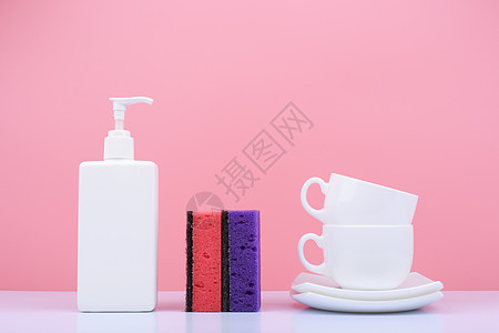 洗碗概念 在明亮的粉红背景下清洗海绵 平板 杯子 清洁剂图片