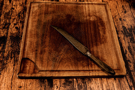 旧木桌上的旧木切板 上面有一把旧刀图片
