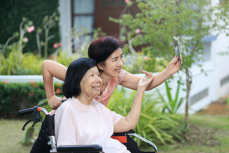 女儿照顾年长的亚洲女人 做自拍 快乐 微笑在后院摄影招待所祖母照片轮椅女士父母母亲家庭照顾者图片