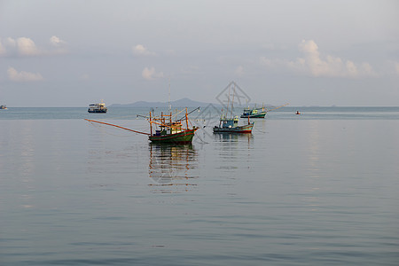 一艘小渔船停靠在岸边的渔捞站后方帆船海滩反射蓝色渔夫海岸钓鱼白色海洋码头图片