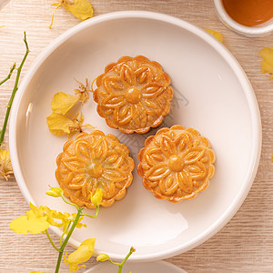 为中秋节准备美味的月亮蛋糕 配有美丽的花朵和茶叶装饰 喜庆午间糕点设计概念平铺兰花节日食物桌子甜点盘子美食木头蛋糕图片