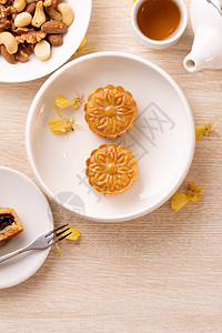 为中秋节准备美味的月亮蛋糕 配有美丽的花朵和茶叶装饰 喜庆午间糕点设计概念蛋糕茶壶杯子木头兰花平铺盘子甜点美食食物图片