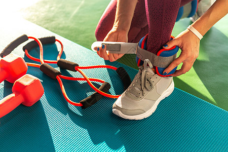 女人在健身 健康和健身概念运动前先戴脚踝护身衣 把哑铃放在垫子上活动娱乐重量女孩女性肌肉袖口配饰训练女士图片