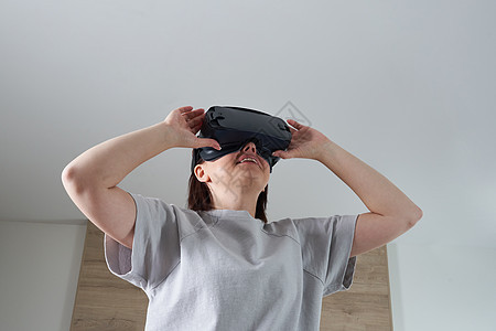 快乐的年轻女人在室内玩 VR 眼镜虚拟现实概念与年轻女孩玩耳机护目镜和复制空间模拟模拟器微笑展示电子乐趣享受成人女性娱乐图片