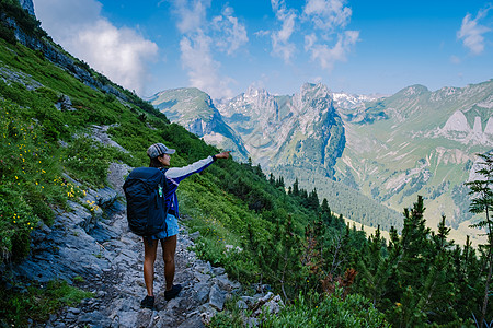 徒步山一个背着背包的女人站在山顶 这个女孩去美丽的地方旅行 到达目标 的山脊 瑞士的 Kreuzberge闲暇游客自由山脉环境生活方式背景