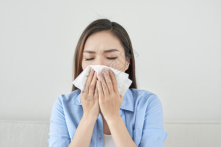 照片上一位生病的年轻女士坐在沙发上吹破她的流鼻涕女孩流感组织医疗成人过敏女性鼻子疾病年轻的高清图片素材