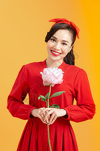 充满欢欣鼓舞的亚洲年轻女性 她满身是玫瑰 站在橙色背景之上眼睛白色成人展示礼服魅力工作室女孩头发红色图片