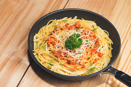 美味的意大利面 番茄酱和肉 在锅木制桌上叶子绿色红色盘子蔬菜食物白色午餐面条草本植物图片