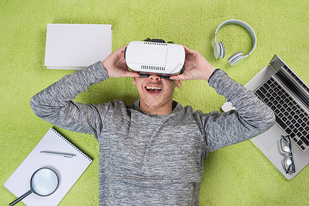 穿着虚拟真人镜的亚洲男人最优视线 躺在地上的男人技术耳机创新工具娱乐眼镜风镜虚拟现实游戏背景图片