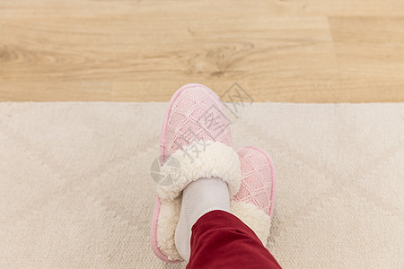 穿着粉红色编织拖鞋的交叉腿地面袜子鞋类卧室小地毯裤子白色女性粉色红色图片