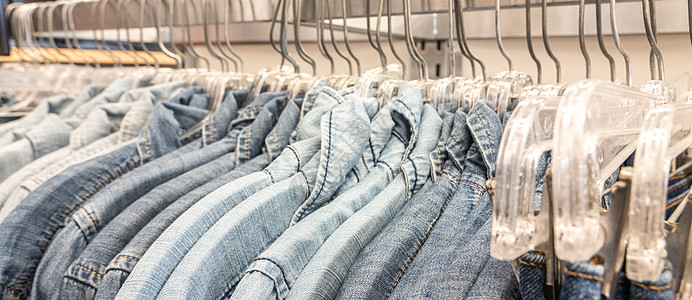 服装分类男性牛仔裤衬衫 在商店衣橱衣柜的铁轨上用衣服衣架进行分类服饰架子材料零售服装织物夹克壁橱裙子纺织品背景
