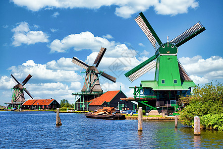 荷兰风车停在靠近荷兰阿姆斯特丹的绿色农村 有蓝天和河流水活力场地房子村庄文化地标桑色历史游客蓝色图片
