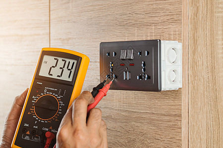 电工用数字仪测量木墙壁插座的电压 在高空上金属安全工具检查力量劳动者维修职业建筑仪表图片