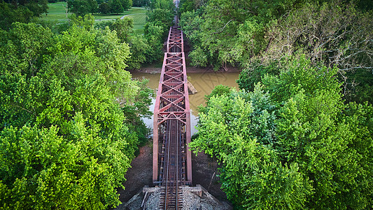 横跨棕河和绿树的紫金属大桥 以铁轨为铁轨图片