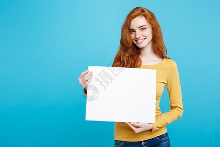 商业概念  特写肖像年轻美丽的有吸引力的姜红发女孩 微笑着显示空白标志 蓝面纸背景 复制空间学生广告快乐女士隐藏人士床单木板商务图片