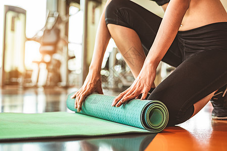 在运动健身健身房训练中心背景下特写运动型女性折叠瑜伽床垫 瑜伽课后保持运动垫滚动 锻炼和运动训练概念 手放在地毯上橡皮娱乐地面运图片