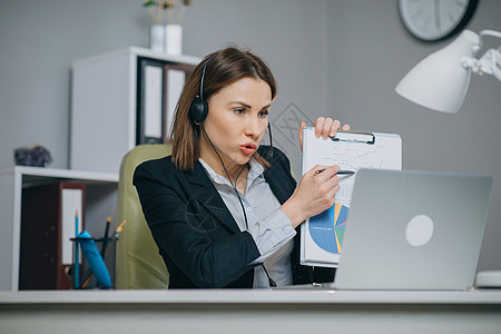 商业女性持有纸质财务报告在网络摄像头的演讲中进行视频呼叫 企业教练在办公室里观看战略 在线培训图片