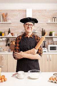 穿围裙的白种老人烘焙厨师训练家庭作坊相机烹饪食物生产面粉图片