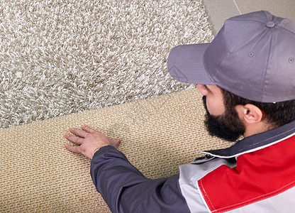 家庭地板上翻滚地毯的男男性工人 从上面看公寓钳工改造地面安装工作房间装修涂层木匠图片