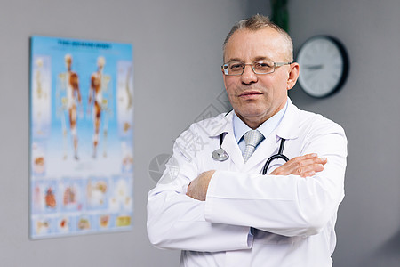 自信周到的高级成年男性专业医生 老医生戴着白色医用大衣眼镜拿着听诊器看着医院办公室的相机 医疗保健和医学概念图片