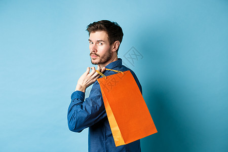 站在蓝色背景上 快乐男人背着购物 向后看的后视图生活成功店铺情绪购物者商业促销工作室胡子广告图片