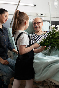 快乐的孙女带花给年长的祖父母孩子家庭长老手术房间游客外科女孩疾病临床病房高清图片素材