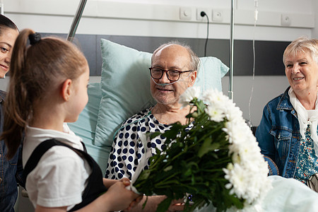 快乐的孙女带花给年长的祖父母花朵女孩孙子疾病惊喜病人游客卫生临床保健老的高清图片素材