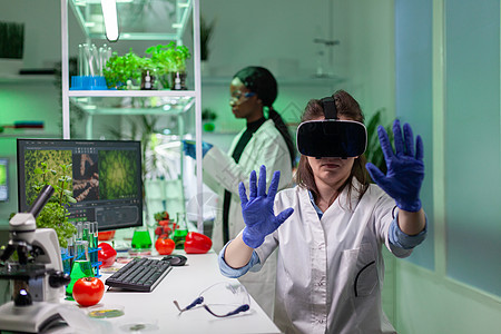 研究新的基因实验的虚拟现实耳机的研究员生物学家技术植物制药女士农业液体管子生物电脑图片