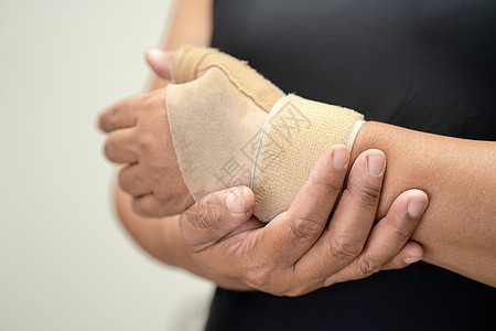 亚洲中年妇女用弹性绷带亲手和手指在办公室治疗德克韦因综合症 20治愈商业成人手臂疾病肌肉症状桌子身体肿胀图片