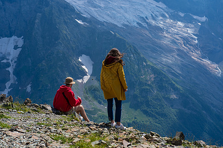 山边的年轻男女在山区欣赏美丽的景色 男坐石 女立 望山景图片