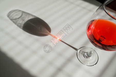 白桌上一杯红酒 遮着百叶窗的阴影反射酒杯酒精饮料口渴餐具盘子水晶酒吧庆典图片