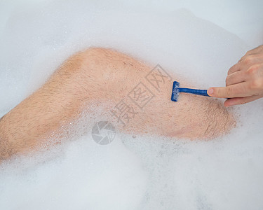 有趣的是 一个男人在洗个放松的澡并刮腿毛 在泡泡浴中 雄性双脚贴近了 顶级风景治疗护理清洁度身体洗澡气泡刺激剃刀剃须泡沫背景图片