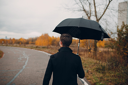 穿黑大衣的年轻人在雨中带着雨伞走来走去公园白色男性女性多云男人红色下雨女士天气图片