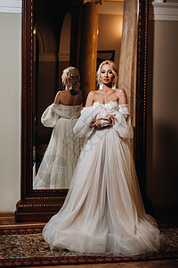一个美丽的新娘的肖像 站在她背对着镜子后面纱裙子花朵嘴唇头发婚姻大厅配件微笑订婚图片