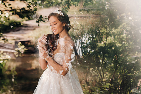 一位穿着白色裙子的优雅新娘 在公园的瀑布上戴着花束的手套 享受着大自然 穿着婚纱和手套的模特在森林里 白俄罗斯旅行婚礼黑发幸福女图片