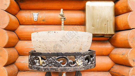 木屋内一个金属制成的摊子上的一块石头洗脸盆 用木头建造的房子内部图片