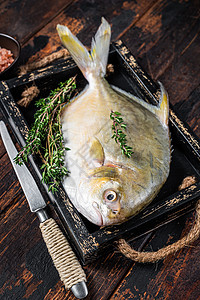 原生鱼黄油鱼或带有木质托盘中草药的龙尾鱼 黑木本底黑色海洋白色美食桌子烹饪黄色营养木板鲳鱼图片