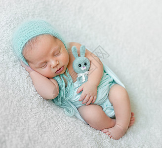 可爱的睡着婴儿 蓝帽子 内裤和玩具说谎尿布孩子毯子灰色新生身体梦幻皮肤生活图片