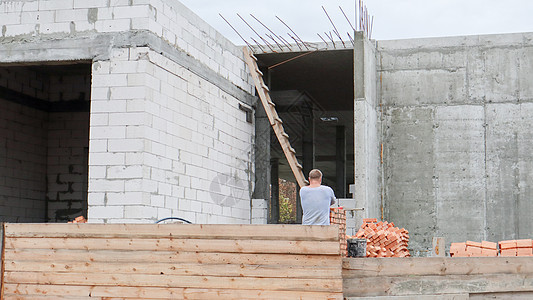 有工人的建筑工地 在木栅栏后面建设中的现代建筑 建设工程 由混凝土和红砖建筑组成的单层建筑图片