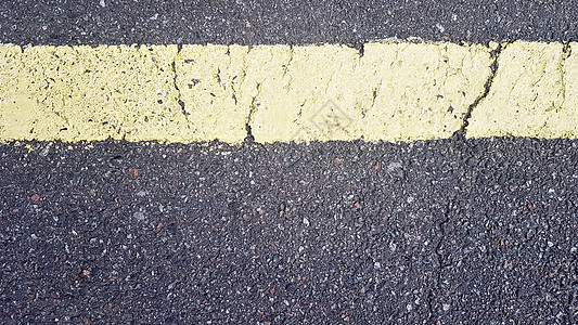 沥青上的黄色水平条 随着时间的推移磨损的黄色条纹的细节 沥青上的道路标记图片