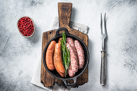 香肠 Chorizo和Bratwurst 配有香料的罗根香肠组装在一个带迷迭香的锅里 白色背景 顶端视图木板红色烧烤美食厨房草本图片