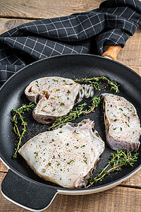 带草药 木本背景的锅盘中新鲜鲜生黑鱼片牛排皮肤食物牛扒美食海狼海洋海鲜白色黑色烹饪图片