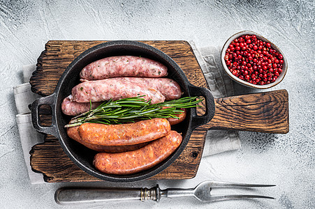 香肠 Chorizo和Bratwurst 配有香料的罗根香肠组装在一个带迷迭香的锅里 白色背景 顶端视图烹饪木板红色屠夫厨房猪肉图片
