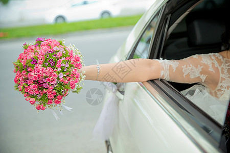 新娘从车里拿出粉红色的花束 新娘女孩走到婚车前 手里拿着一束花挥手致意 新娘的花束 婚礼当天图片