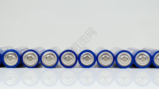 许多AA碱性电池在白色的光滑背景上 反射与复制空间排成一行图片