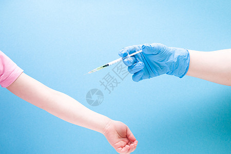 蓝色橡胶医用手套中的女性手在蓝色背景复制空间 治疗和保健概念 儿童糖尿病概念上用胰岛素注射器给小女孩注射图片