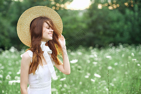 穿着白色衣服的快乐女人 在自然花上散步公园享受晴天自由微笑女性阳光女孩草地皮肤图片