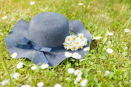 蓝色帽子躺在绿色草地上 上面有小花朵 鲜花和草原花束 浪漫的夏季时光照片 假期概念图片