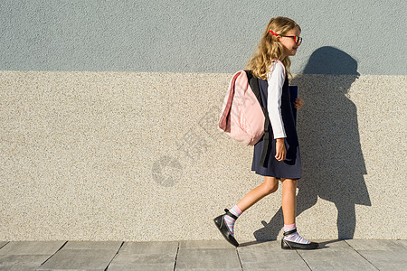 他手里拿着笔记本的小学女学生 一个背着背包的女孩去上学 回到学校图片